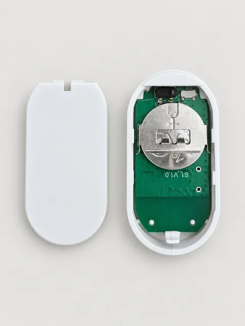 Open sensor battery compartment with the coin cell seated under the metal holder and the plus side facing outward